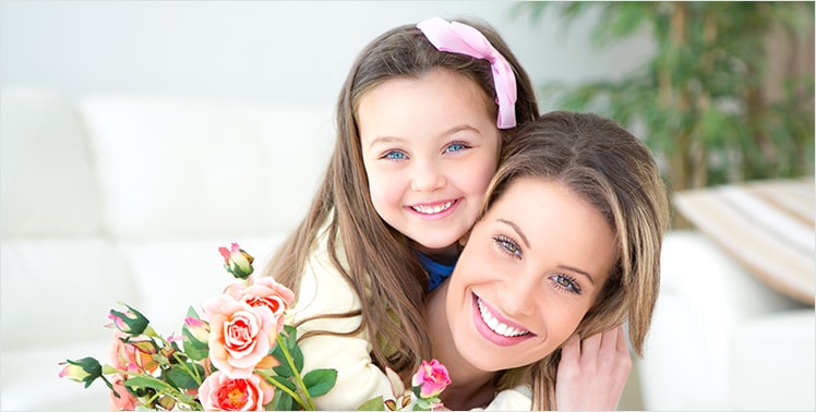 Mother and daughter smiling in a patio area with beautiful flowers